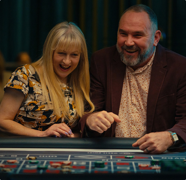 Joyful couple laughing and enjoying a game at Wrest Point Casino in Hobart, sharing a fun moment at the gaming table.