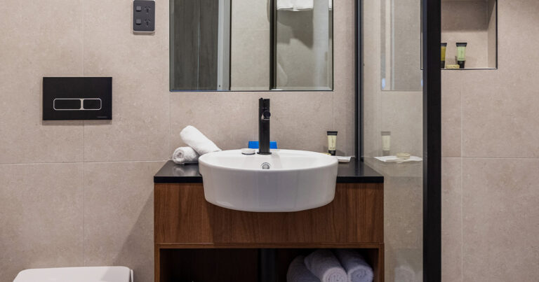 Modern bathroom at Wrest Point featuring a round sink, contemporary fixtures and a large mirror, reflecting a clean and stylish design.